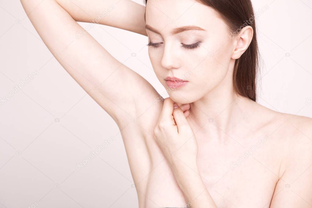 Close up young woman showing and touching her smooth axilla.