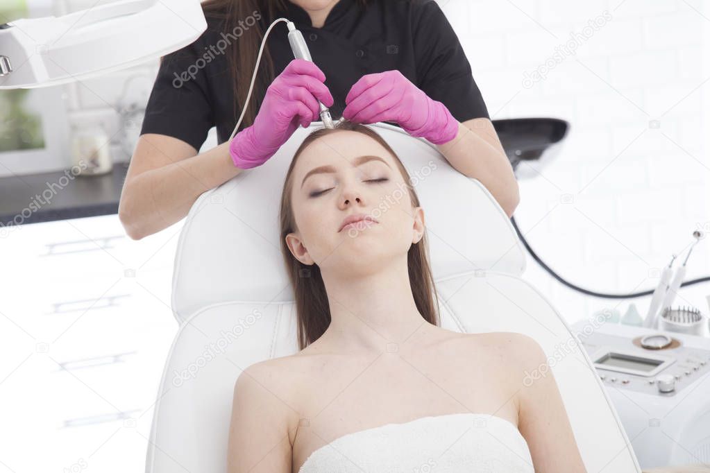 Beautiful, young woman having a treatment of her head's skin.