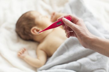 Küçük bebek hasta. Anne tarafından elektronik termometre vücut ısısı ölçme.