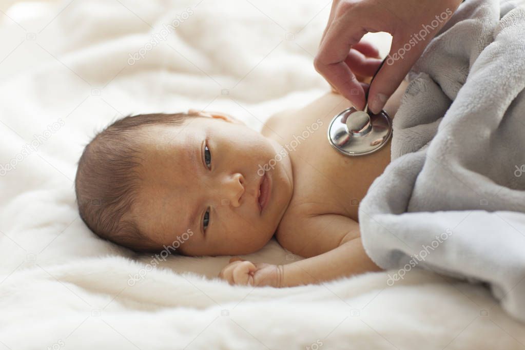 Let's listen a heartbeat. Young doctor examining a baby.