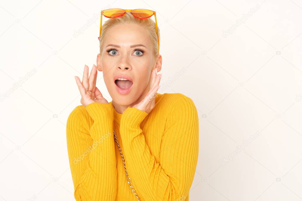 Blonde woman in yellow sweater is shocked.
