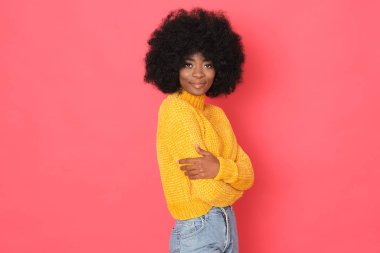 Güzel bir Afro-Amerikan modeli. Kırmızı arka planda izole edilmiş nazik bir gülümsemesi var..