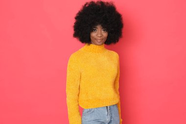 Güzel bir Afro-Amerikan modeli. Kırmızı arka planda izole edilmiş nazik bir gülümsemesi var..