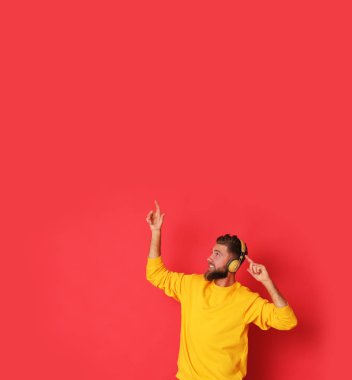 Sarı bluzlu genç bir adam müzik dinliyor..