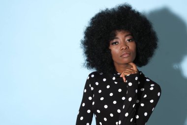 Siyah golfte Afro-Amerikan modeli. Mavi arka planda beyaz noktalar var..