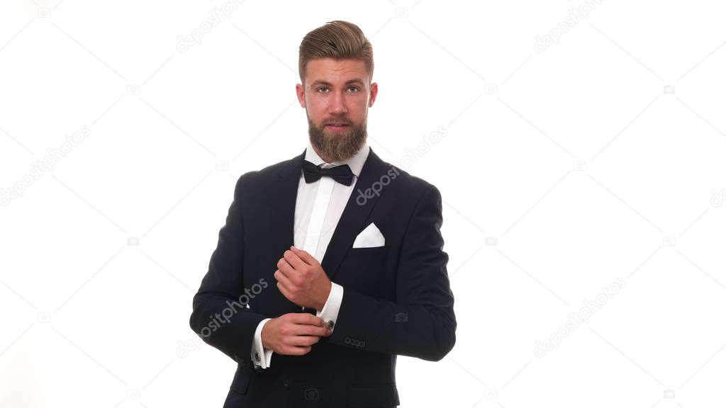 Good looking young man with beard wearing classic black suit, isolated on white background.