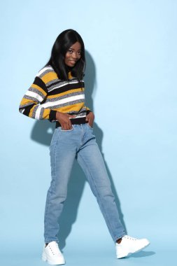 Fashion model in strike a pose wearing nice striped, colorful sweater.