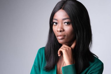 Gri arka planda izole edilmiş siyah kısa saçlı sevimli ve güzel Afro-Amerikan modelinin portresi..