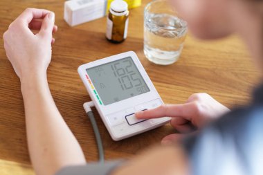 Yüksek tansiyonu olan genç bir kadın tansiyonunu kontrol ediyor..