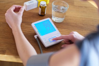 Yüksek tansiyonu olan genç bir kadın tansiyonunu kontrol ediyor..