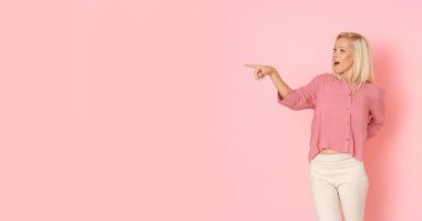 Mutlu, sarışın, pembe tişörtlü güzel kız bir şeyler gösteriyor..