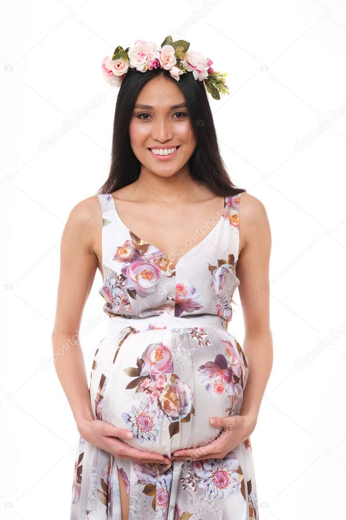 The picture of beautiful asian, pregnant  woman in long dress and flower crown on head.