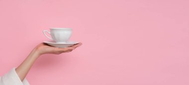 Kahve lütfen. Pembe arka planda bir fincan kahve tutan kadın. Şarj etme zamanı..