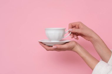 Kahve lütfen. Pembe arka planda bir fincan kahve tutan kadın. Şarj etme zamanı..