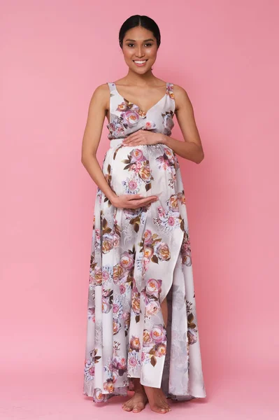 Beautiful asian model in long dress showing her pregnant belly looks amazing