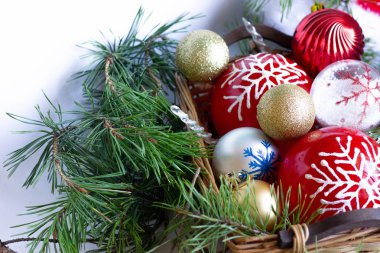 Tahta bir sepetin içinde Noel topları. Çam ağacının yeşil dalları,