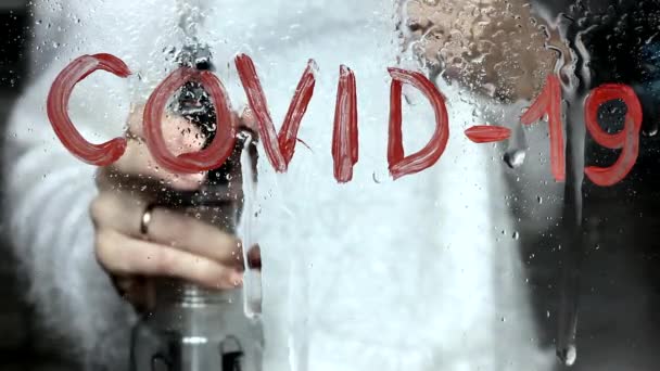 Напис на склі з червоною фарбою COVID-19 змивається водою, рука з пляшкою розпилювача, вірус вільний — стокове відео