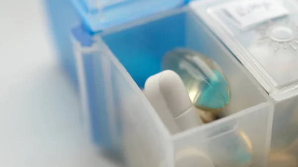 Pills lying in a blue cell of a white pill box — Stock Photo, Image