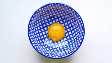Mavi-beyaz desenli derin bir tabakta çiğ yumurta sarısı.