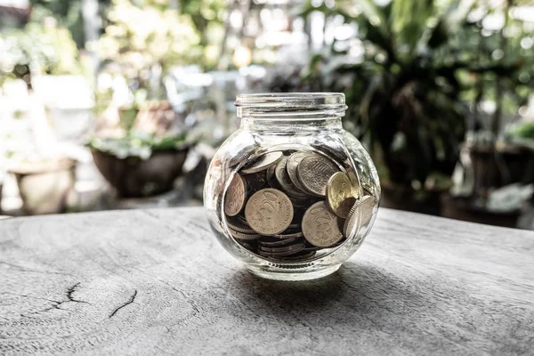 Glass jar piggy bank with coins. Plan your savings, run a growing business for success and save for retirement