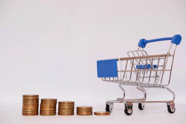 Carrinho azul com pilha de moedas, economizando dinheiro para fazer compras em seu conceito de férias — Fotografia de Stock