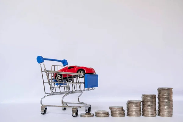 Rotes Auto in blauem Einkaufswagen mit Münzstapel, spart Geld für Neuwagenkauf und Versicherungskonzept — Stockfoto