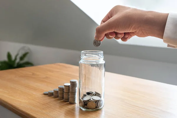 Hombres de negocios depositando monedas En una botella de vidrio junto a la carta de monedas, expandiendo un negocio exitoso y económico para los conceptos de jubilación — Foto de Stock