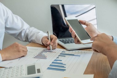 Sonuçları gösteren çizelge ve grafikleri tartışan iki iş lideri büyük başarı için yeni bir strateji başlatmayı planlıyor.