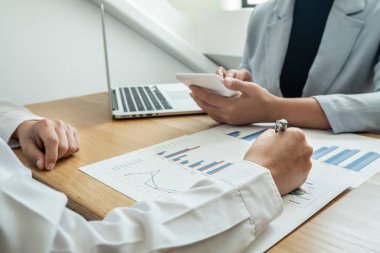 Sonuçları gösteren çizelge ve grafikleri tartışan iki iş lideri büyük başarı için yeni bir strateji başlatmayı planlıyor.