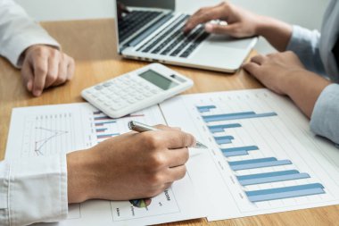 Sonuçları gösteren çizelge ve grafikleri tartışan iki iş lideri büyük başarı için yeni bir strateji başlatmayı planlıyor.