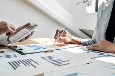 Sonuçları gösteren çizelge ve grafikleri tartışan iki iş lideri büyük başarı için yeni bir strateji başlatmayı planlıyor.