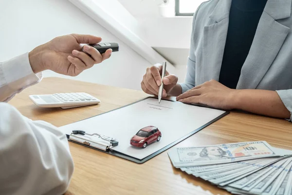 Car dealership provides advice about insurance details and car rental information and delivers the keys after signing the rental contract