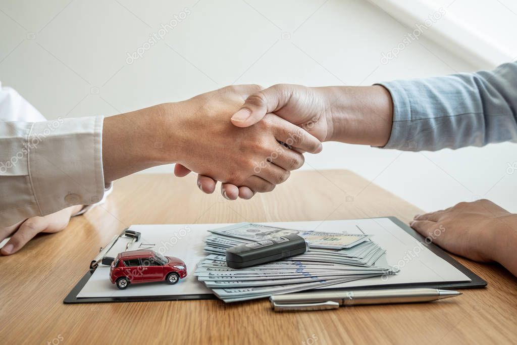 Shaking hand,Car dealership provides advice about insurance details and car rental information and delivers the keys after signing the rental contract