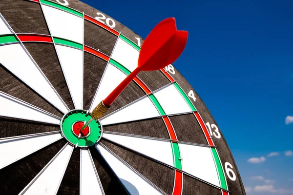 Dart arrow hit on bulleyes of dartboard with blue sky, Planning new business target and goals