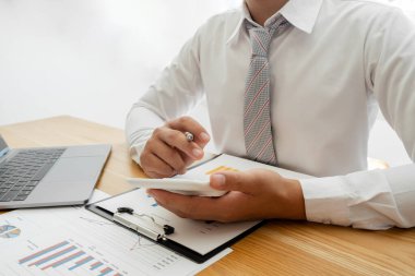 Bir iş adamı masada oturuyor ve gayrimenkul yatırımlarının finansal grafiklerini hesaplıyor.