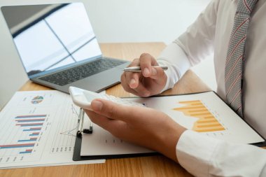 Bir iş adamı masada oturuyor ve gayrimenkul yatırımlarının finansal grafiklerini hesaplıyor.