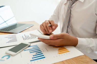 Bir iş adamı masada oturuyor ve gayrimenkul yatırımlarının finansal grafiklerini hesaplıyor.