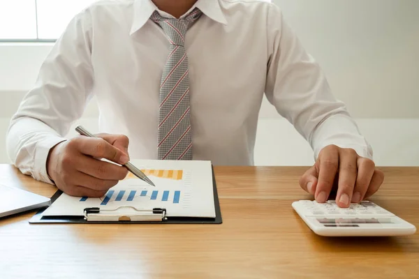 A business man is sitting at a desk and calculating financial graphs about real estate investment expenditures — Stock Photo, Image