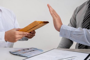 İş adamı, rüşvet ve yolsuzluk kavramına rüşvet vermek için ortağı tarafından önerilen zarftaki parayı reddediyor.