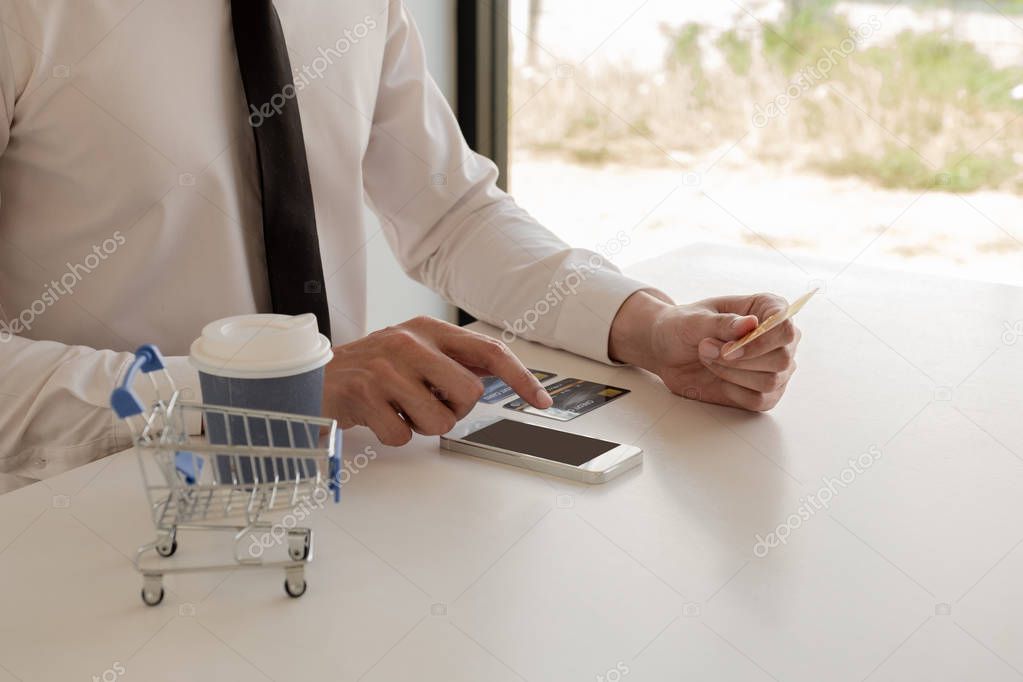 The hands of business people holding credit cards and use smartphones for online shopping and paying via the internet.