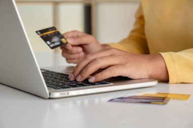 Genç bayan internet üzerinden alışveriş yapmak ve ödemeleri yapmak için kredi kartı ve dizüstü bilgisayar kullanıyor..