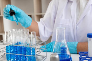 Tıp bilimcileri bir kimya laboratuvarında virüsü analiz etmek için test tüpüne bir örnek pipet yerleştirdiler. Bilimsel araştırma kavramları.