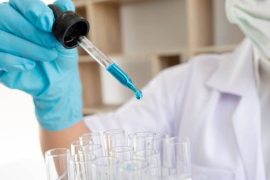 Tıp bilimcileri bir kimya laboratuvarında virüsü analiz etmek için test tüpüne bir örnek pipet yerleştirdiler. Bilimsel araştırma kavramları.