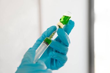 Tıp bilimcileri sıvı bir aşı şişesi ve şırıngayı bir kimyasal laboratuvar bilimsel araştırma konseptinde tutuyorlar..