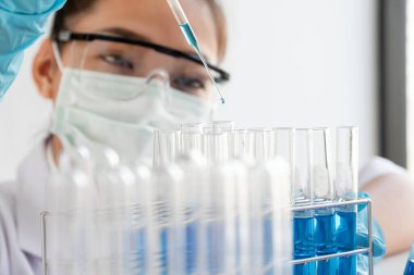 Tıp bilimcileri bir kimya laboratuvarında virüsü analiz etmek için test tüpüne bir örnek pipet yerleştirdiler. Bilimsel araştırma kavramları.
