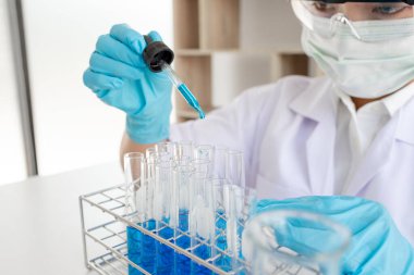 Tıp bilimcileri bir kimya laboratuvarında virüsü analiz etmek için test tüpüne bir örnek pipet yerleştirdiler. Bilimsel araştırma kavramları.