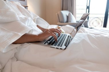 Genç bir kadının eli rahat bir odada dizüstü bilgisayarla oynayıp meyve hazırlıyor..