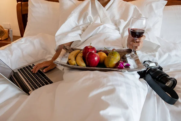 스러운 방에서 맛있는 과일을 먹으며 노트북을 연주하는 여성의 — 스톡 사진