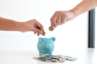 İki el domuz kumbarasına madeni para koyuyor. Para biriktiriyorlar. Başarılı olmak ve emeklilik için biriktirmek üzere büyüyen bir işe adım atıyorlar..