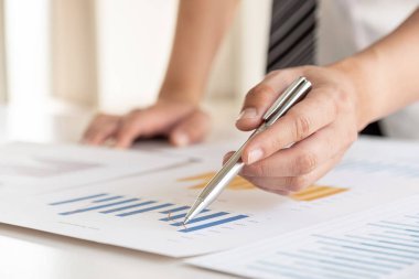 Bir iş adamı masada oturuyor ve gayrimenkul yatırımlarının finansal grafiklerini hesaplıyor..